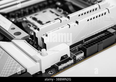 Moduli RAM bianchi installati in una scheda madre moderna, che evidenziano l'ingegneria di precisione e l'elegante design dei componenti del PC. Foto Stock