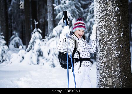 Giovane donna che fa trekking in una foresta innevata Foto Stock
