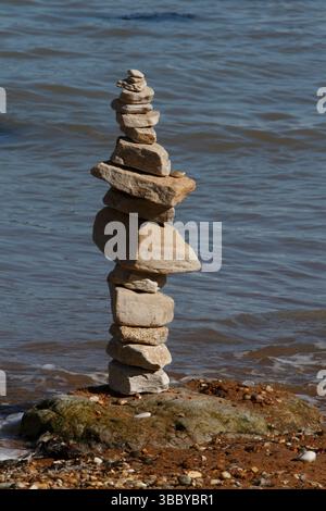 Cairn su una spiaggia con la marea in arrivo. Foto Stock