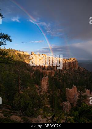 Arcobaleno colorato che si innalza sopra gli hoodoos del Bryce Canyon dopo una tempesta estiva, con un cielo spettacolare e un paesaggio panoramico di rocce rosse, Utah, Stati Uniti Foto Stock