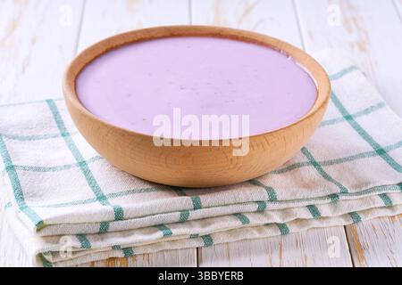 frullato di mirtilli in una ciotola di legno su un tavolo bianco, messa a fuoco selettiva. Foto Stock