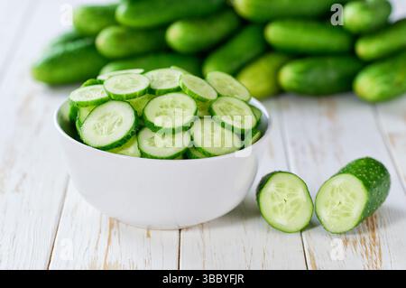 I cetrioli organici tagliano a fette in un recipiente di ceramica su un tavolo leggero, con messa a fuoco selettiva. Foto Stock