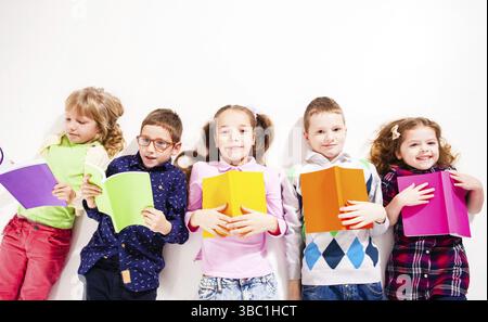 Vista dall'alto di bambini sono sdraiato sul pavimento con colorati libri sullo sfondo bianco Foto Stock