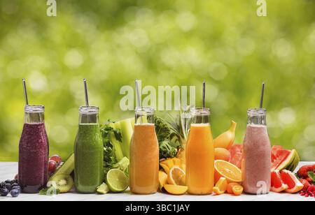 Frullati con tubi in glasse all'aperto. Le bottiglie si stano in un mucchio con i frutti tropicali affettati sul tavolo Foto Stock