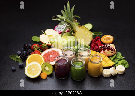 Gruppo di vari frullati di frutta in bicchieri, verdure e frutta su sfondo nero Foto Stock