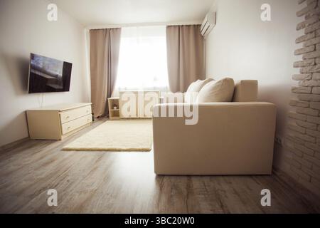 Interni moderni in stile minimalistico con salotto in tonalità beige. Confortevole soggiorno con aria condizionata Foto Stock