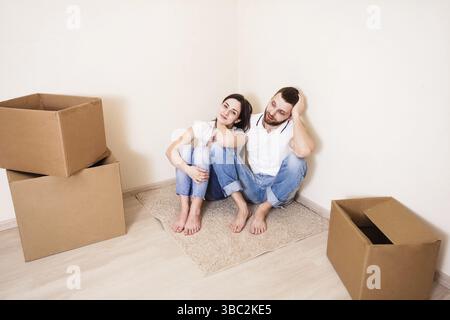 La giovane coppia seduta sul pavimento, appoggiata contro il muro accanto alle caselle Foto Stock