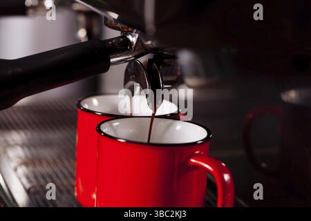 La macchina per caffè automatica produce due caffè espresso in tazze rosse vintage Foto Stock