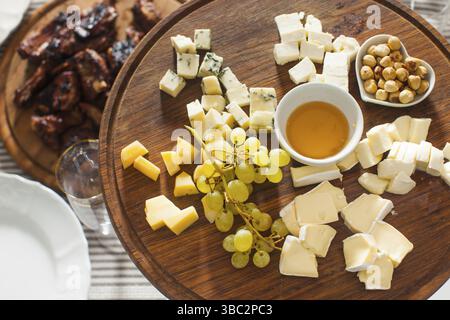 Il piatto di formaggi con nocciole, miele, uva sulla tavola di legno sul tavolo serviti Foto Stock