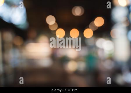Un caffè blur Cafe' con sfondo bokeh offuscato immagine di intimo spazio interno con calde luci sospese che creano un'atmosfera morbida e invitante Foto Stock
