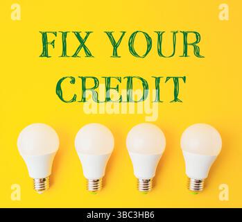 Quattro lampadine bianche su sfondo giallo con sopra la scritta "Fix Your Credit" Foto Stock