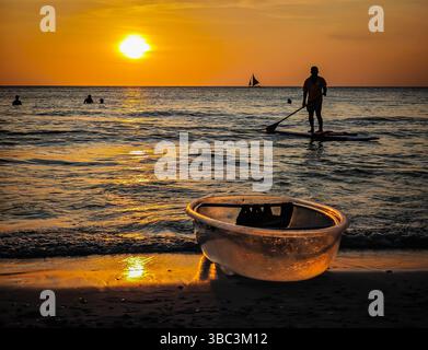 Bambini filippini che navigano di fronte a un tramonto dorato sull'isola di Boracay di fronte alle barche nelle splendide acque marine di Boracay Foto Stock