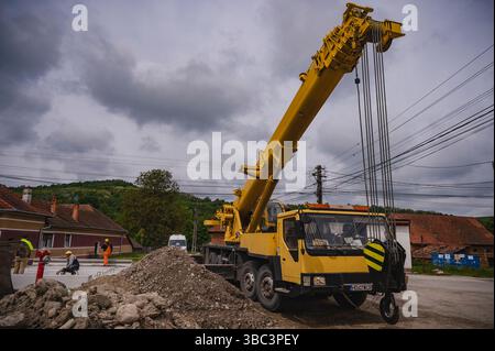 Orastioara de Sus, Romania - 12 maggio 2025: Gru mobile gialla su un cantiere in Romania rurale. Foto Stock