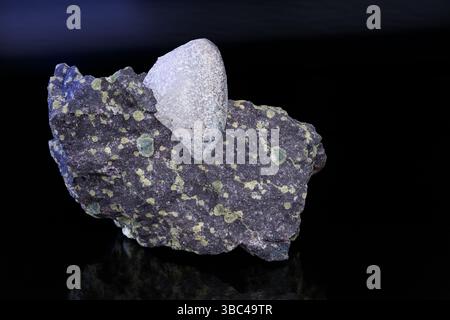 Gemma di agata naturale in melaura con amigduli verdi su sfondo scuro e lucido. Nodulo di gemme non tagliate in roccia ignea vulcanica estrusiva di basalto. Foto Stock