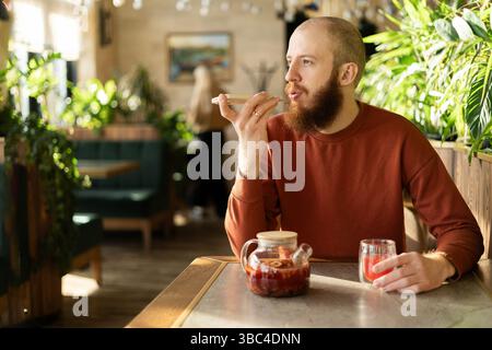 Uomo che detta un messaggio vocale mentre si gusta un tè Foto Stock