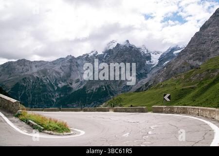 Uno dei tornanti iconici del passo dello Stelvio, con cime rocciose e ghiacciai sullo sfondo Foto Stock