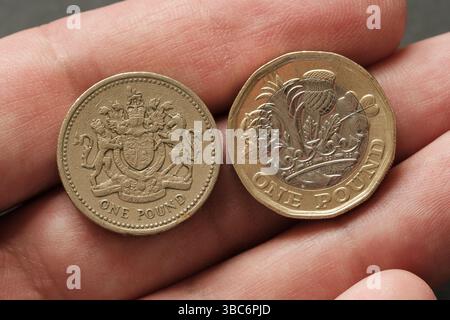 Confronto ravvicinato tra monete vecchie e nuove da una sterlina tenute in mano, evidenziando l'evoluzione del design valutario britannico e delle caratteristiche di sicurezza, Stafford Foto Stock