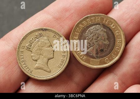 Vista ravvicinata del ritratto della regina Elisabetta II sulle vecchie e nuove monete inglesi da una sterlina tenute in mano, che illustrano i cambiamenti nella monetazione e nell'effigie reale, St Foto Stock