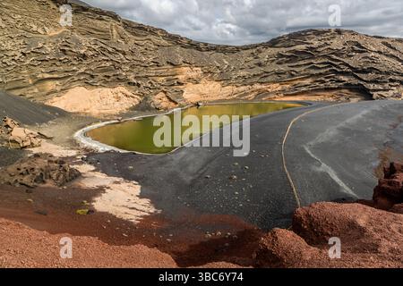 Il lago di cratere verde Charco de los Clicos si trova tra una spiaggia di sabbia nera e pareti rocciose rosse vicino a El Golfo a Lanzarote, Yaiza, Isole Canarie, Spagna. Il colore proviene dalle alghe sul fondale del lago. Foto Stock