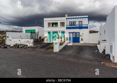 Case bianche su Lanzarote con cornici delle finestre verdi e blu. I colori sono fissi: Blu per i pescatori, verde per l'agricoltura e marrone per gli artigiani. Avenida Marítima, El Golfo, Canarias, Spagna Foto Stock