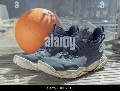 Londra, Regno Unito - 17 maggio 2025 - scarpe da pallacanestro e palla da basket vengono posizionate sul balcone, dopo l'allenamento da basket. Usala come Wal Foto Stock