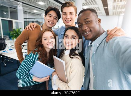 Felici studenti internazionali che prendono selfie all'università Foto Stock