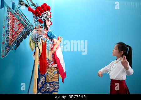 Pechino, la provincia cinese di Jiangsu. 18 maggio 2025. Una ragazza imita il gesto di una scultura in un museo dell'opera tradizionale a Kunshan, nella provincia cinese di Jiangsu, 18 maggio 2025. Crediti: Wang Xuzhong/Xinhua/Alamy Live News Foto Stock