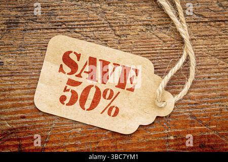 Risparmia il 50% firmando un cartellino del prezzo della carta contro il legno di fienile rustico dipinto di rosso - concetto di shopping Foto Stock