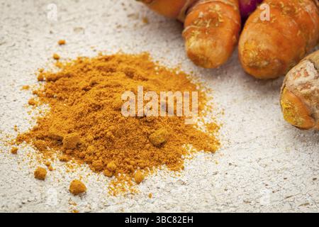 Polvere di curcuma e radice su una superficie di legno grezzo verniciata di bianco Foto Stock