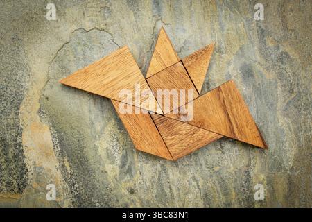 Immagine astratta di un pipistrello volante costruito con sette pezzi di legno tangram su uno sfondo di ardesia, Halloween Concept, opera d'arte creata dalla foto Foto Stock