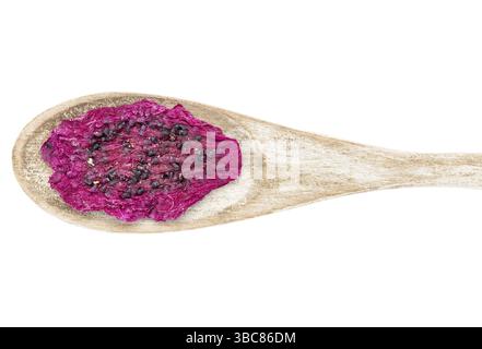 Una fetta di frutta rossa essiccata su un cucchiaio di legno rustico Foto Stock