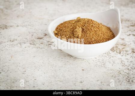 Piccola ciotola in ceramica con zucchero di palma da cocco non raffinato su uno sfondo piastrellato in ceramica con uno spazio di copia Foto Stock