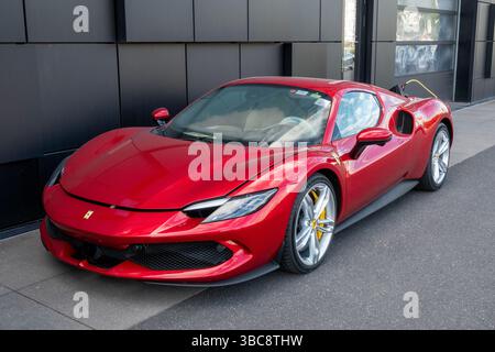 A red Ferrari 296 sports car with V6 engine coupled with a plug-in electric motor is refueled with an electric charger. Copenhagen, Denmark - May 15, Foto Stock