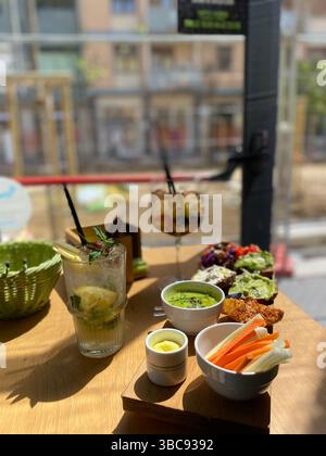 Cocktail rinfrescanti e vari antipasti sono serviti su un tavolo di legno in un ristorante a Pescara, in Italia, creando una piacevole esperienza aperitivo Foto Stock