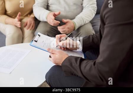 Avvocato manager in abbigliamento formale che scrivono nei documenti, preparando il contratto assicurativo Foto Stock