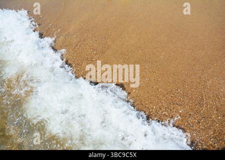 La schiuma delle onde marine scorre sulla sabbia marina. Bellissima spiaggia di sabbia marina con sfondo a onde marine e spazio per copiare Foto Stock