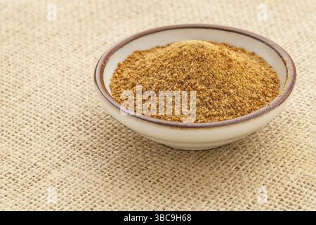 Piccola ciotola in ceramica con zucchero di palma da cocco non raffinato su una tela di burlap Foto Stock