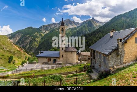 Una vista panoramica panoramica di una chiesa in pietra nel villaggio montano di Ferrere in una valle delle Alpi italiane, in Piemonte. Foto Stock