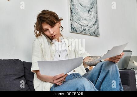 Uno studente analizza i documenti al telefono in un ambiente domestico rilassato. Foto Stock