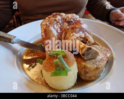 Cosce di maiale stufato con salsa di sugo dolce, nocciolo di maiale e contorni piatti in stile bavarese. Monaco, Germania, 2022 Foto Stock