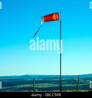 Una calza a vento strappata si erge in rilievo su un palo in Alvernia, soffiando dolcemente nella brezza. Francia Foto Stock