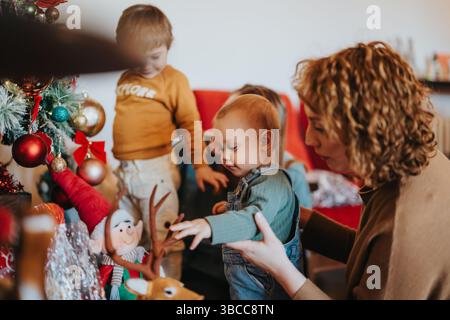 Una famiglia ama decorare un albero di Natale a casa insieme Foto Stock