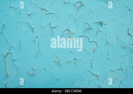 Vecchia parete con vernice blu sbucciante. Sfondo esterno della parete in cemento con sbucciatura della vernice blu. Vernice incrinata sul muro. Foto Stock