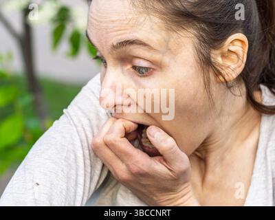 Un primo piano di una zecca di cervo trovata strisciando intorno al braccio di una persona. L'aracnide è di colore rossastro e le sue gambe si allungano mentre strisciano Foto Stock