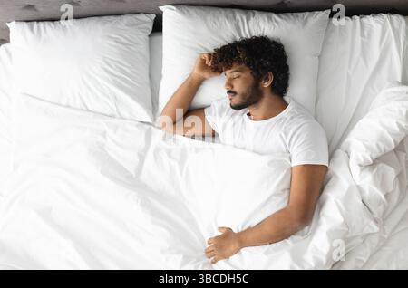 Vista dall'alto di un ragazzo indù che dorme da solo a letto Foto Stock