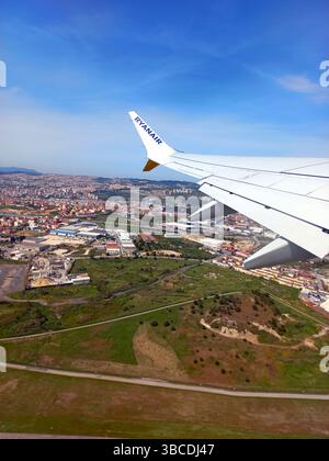 Spagna. 12 aprile 2023 Ala di un aereo Ryanair durante la discesa mostrando un vasto paesaggio urbano e una campagna aperta sotto un cielo azzurro Foto Stock