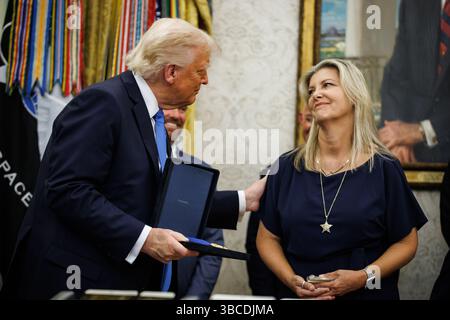 Il presidente DEGLI STATI UNITI Donald Trump presenta una Medaglia del sacrificio a Denise Waller in onore di suo marito, il vice sceriffo della contea di Palm Beach Ralph "Butch" Waller Jr., deceduto nell'adempimento del dovere, durante un evento con familiari di funzionari delle forze dell'ordine caduti nell'ufficio ovale della Casa Bianca a Washington, DC, USA, lunedì 19 maggio, 2025. Trump oggi ha detto che Mosca e Kiev avrebbero iniziato i colloqui "immediatamente" sulla fine della guerra in Ucraina dopo una telefonata con il presidente russo lunedì. Fotografo: Samuel Corum/Pool/Sipa USA Foto Stock