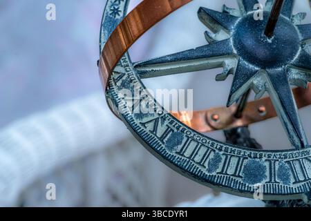 Primo piano di una sfera armillare decorativa o di una meridiana con numeri romani, fascia in rame e design a bussola in luce naturale. Foto Stock