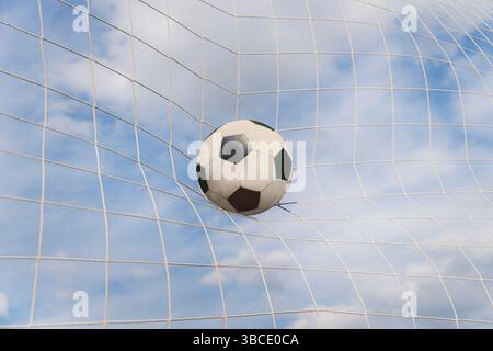 campo da calcio con una palla in porta contro un cielo nuvoloso. Foto Stock