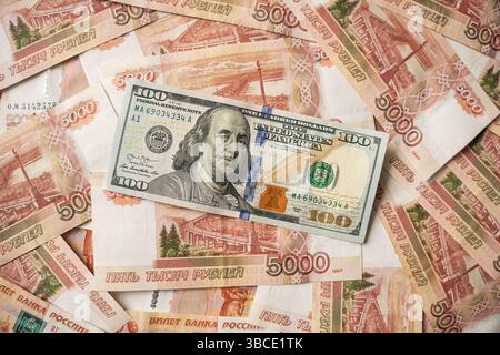 Nuova banconota da cento dollari e rubli russi. Una banconota da cento dollari è su una grande pila di rubli russi in tagli da 5000. Foto Stock
